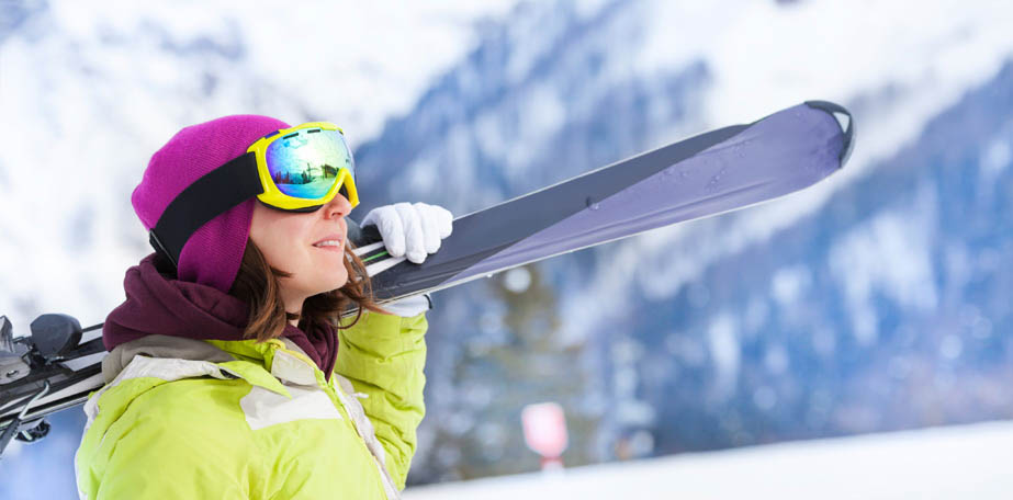 Girl in mask stands and holds ski during day